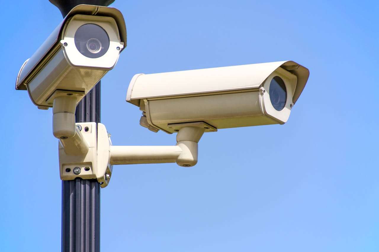 White 2 Cctv Camera Mounted on Black Post Under Clear Blue Sky